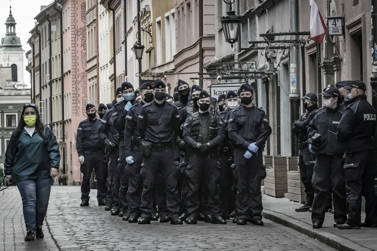 Woman in a blue hooded coat facing a line of police officers